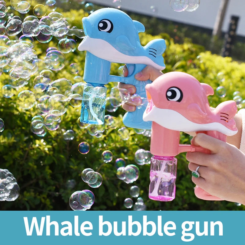 Two whale-shaped bubble guns, one blue and one pink, being used to blow bubbles outdoors.