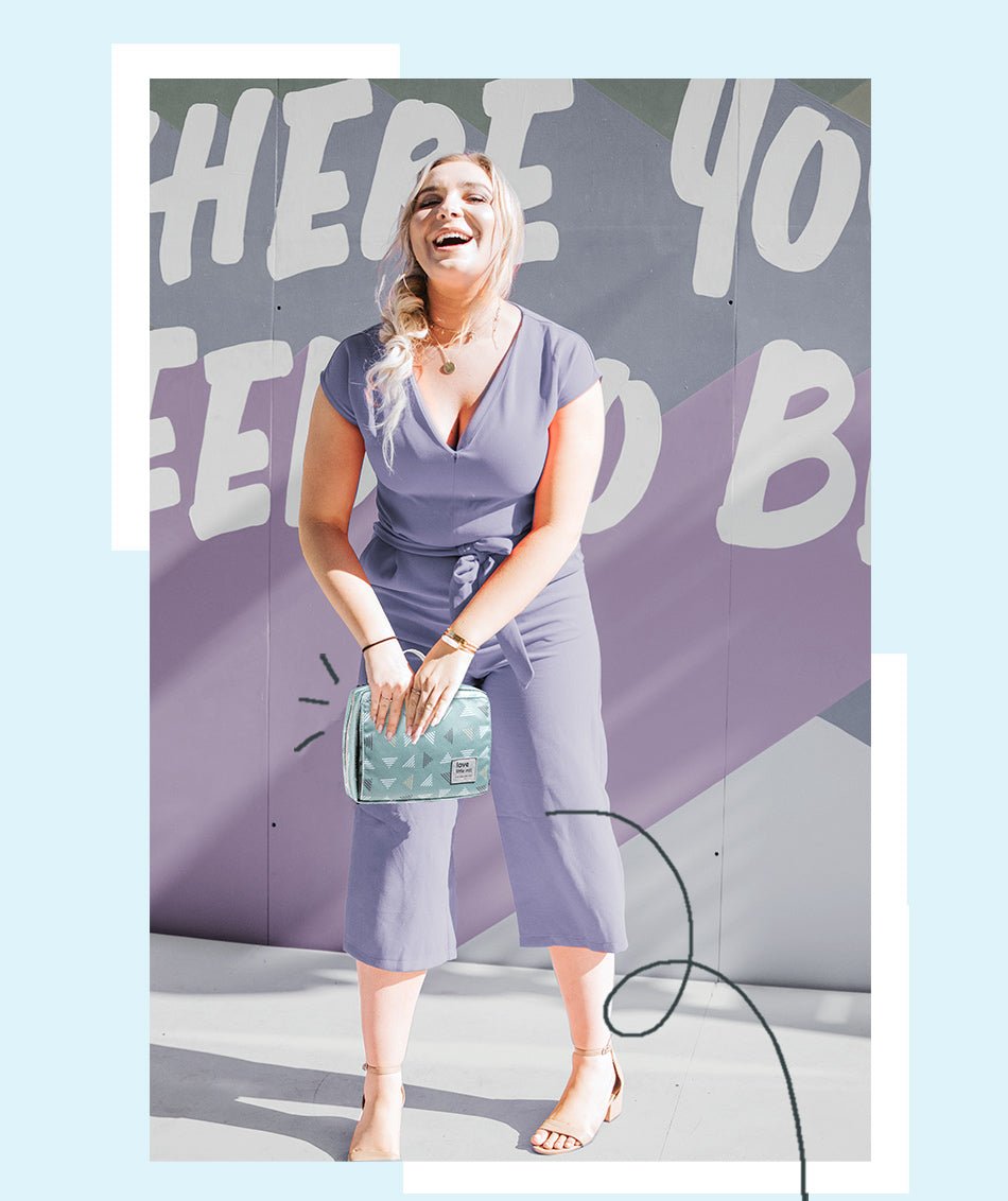 Woman in a purple outfit holding a turquoise clutch against a colorful background
