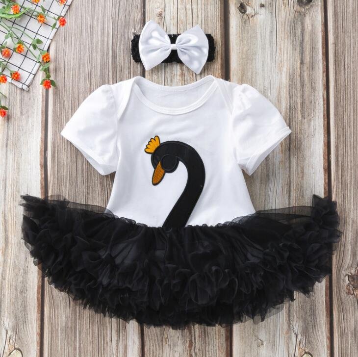 Baby outfit with black swan design on a white shirt, black tutu skirt, and white bow headband