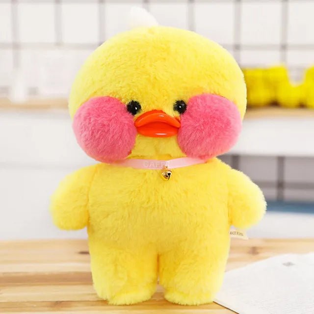 Yellow plush duck with pink cheeks on a wooden surface