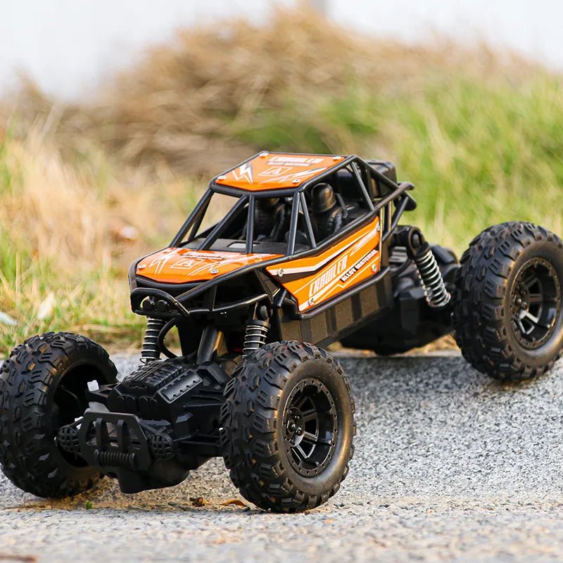 Orange and black remote control monster truck on a gravel surface