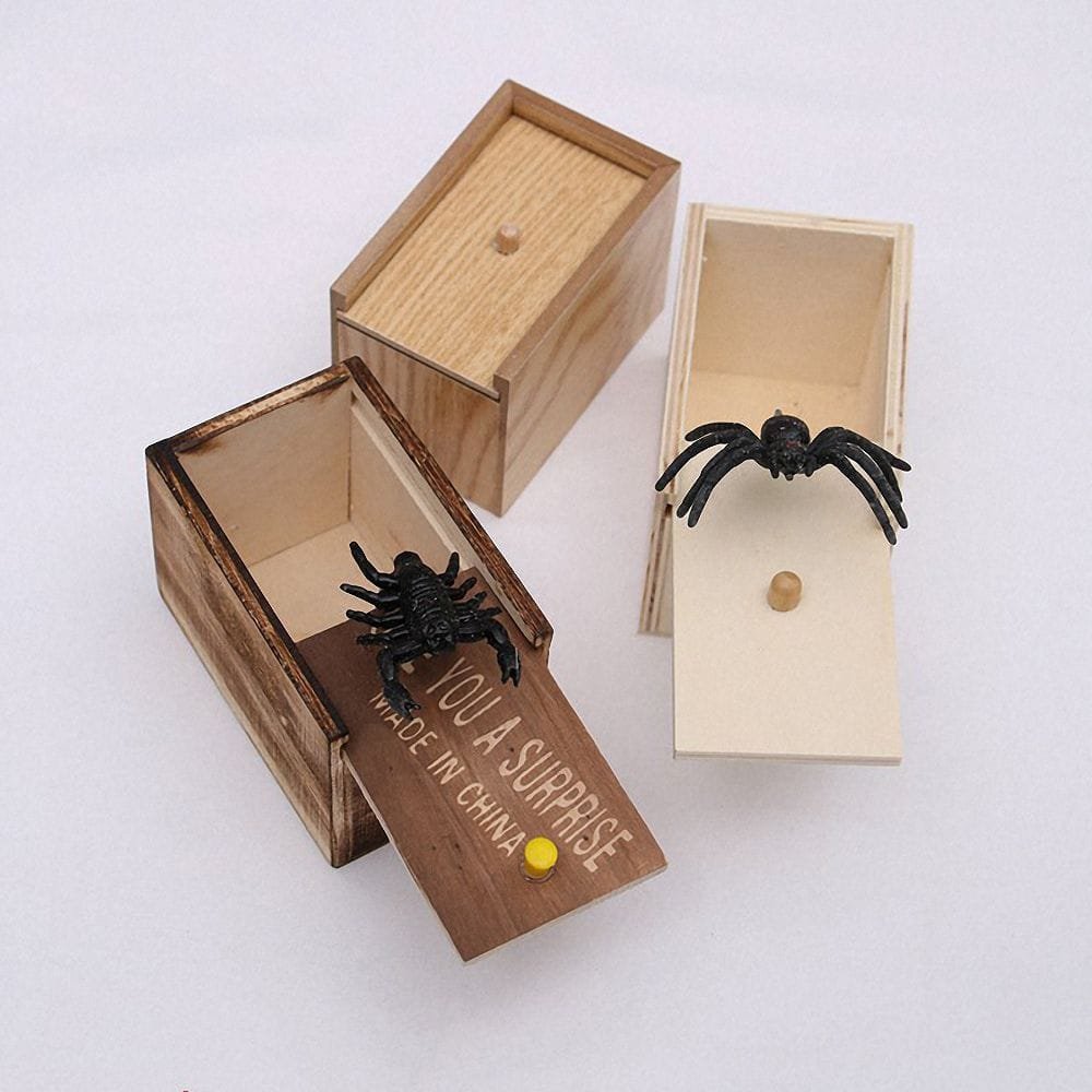 Wooden box with a spider toy and a small wooden ball, on a white background.