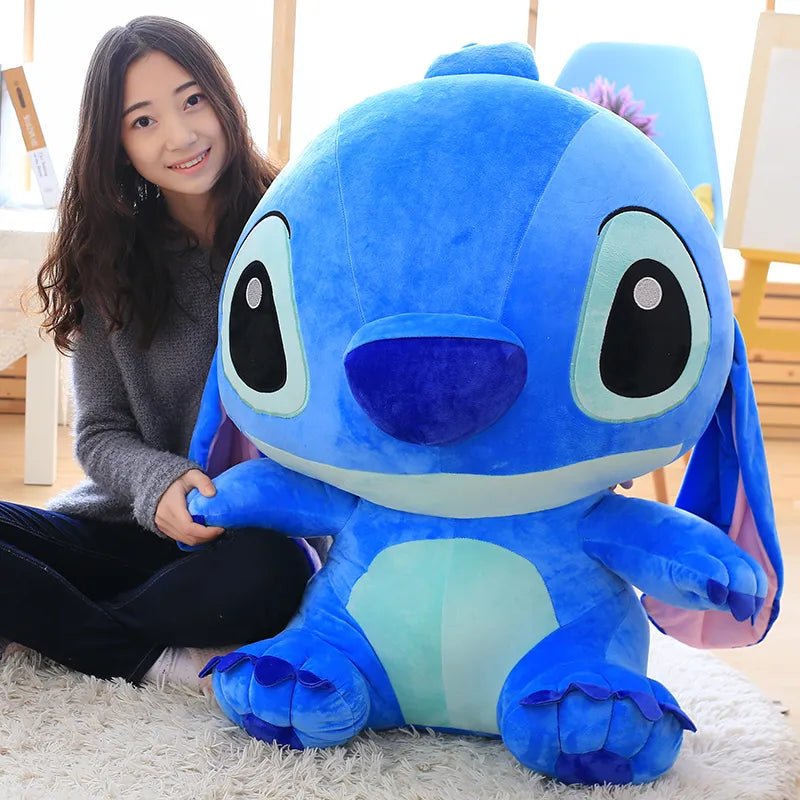 Person holding a large blue plush toy resembling a character from an animated movie.