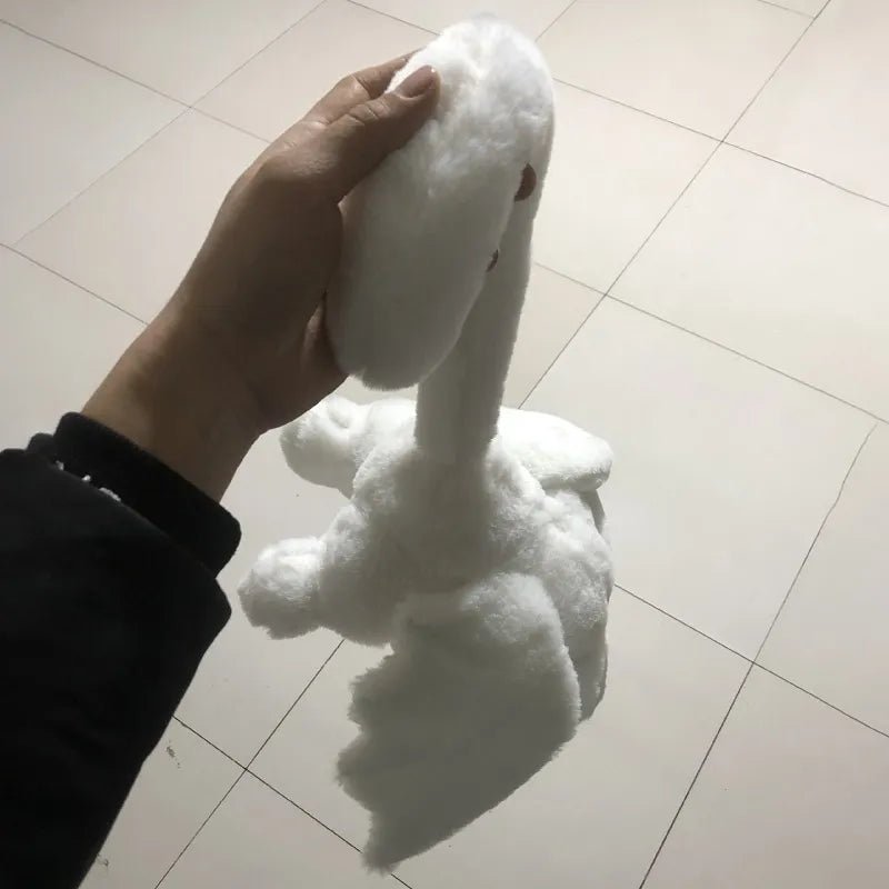 White plush toy resembling a swan held by a hand on a tiled floor.