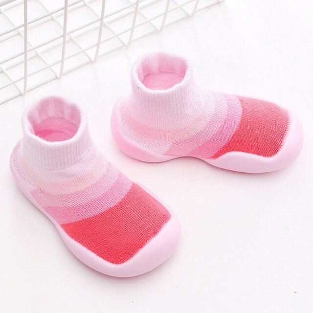 Pair of pink and white baby socks on a light background