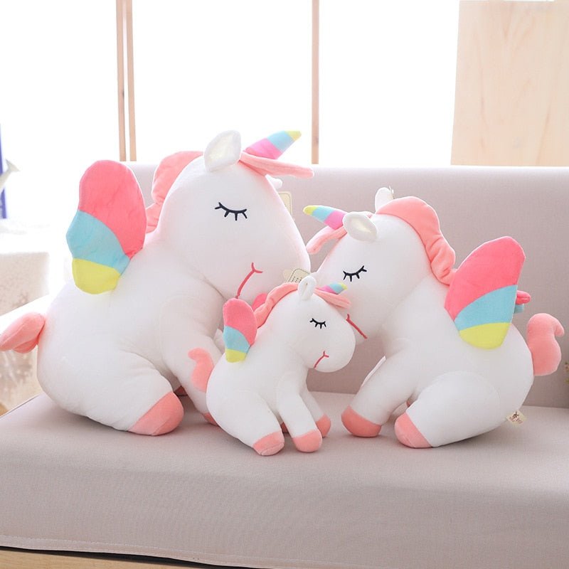 Set of unicorn-shaped pillows with colorful accents on a light-colored couch.
