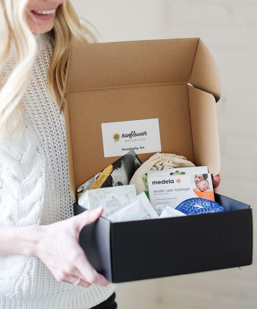 Person holding a box with baby care products including Medela and Sunflower Baby.