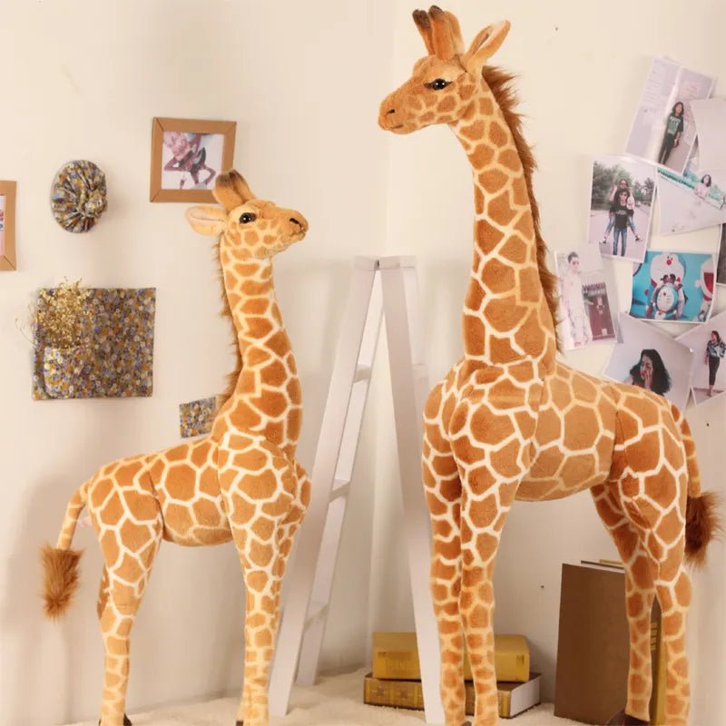 Two large stuffed giraffes in a room with decorative items on the wall.
