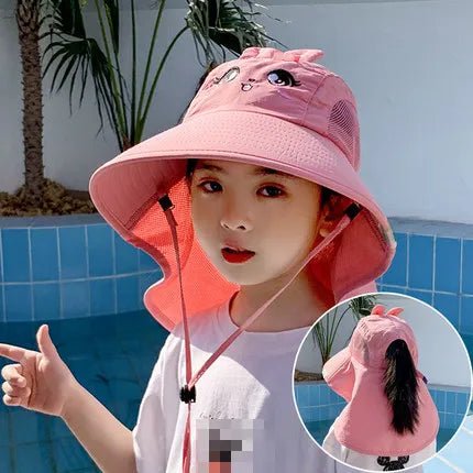 Child wearing a pink sun hat with a face design, standing by a pool.