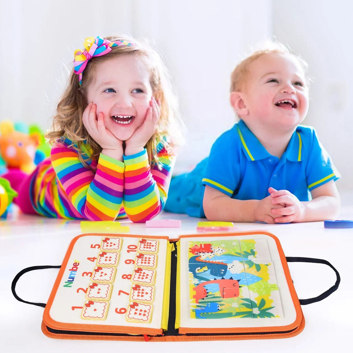 Two children sitting at a table with a colorful educational book open in front of them.