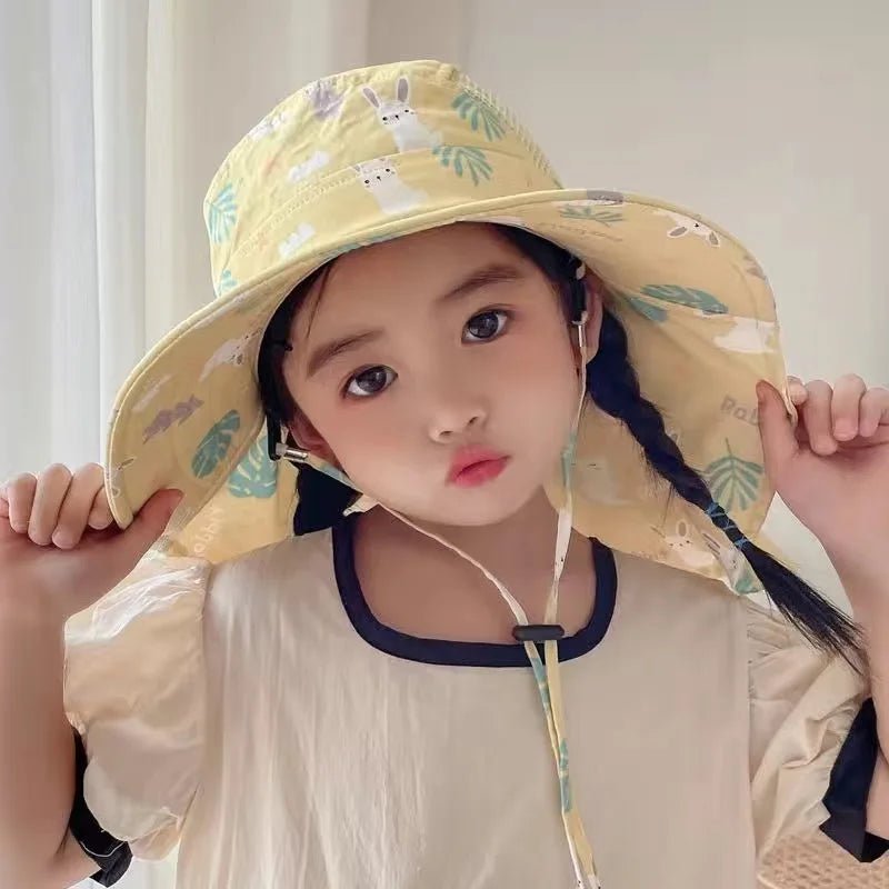 Child wearing a yellow patterned sun hat indoors