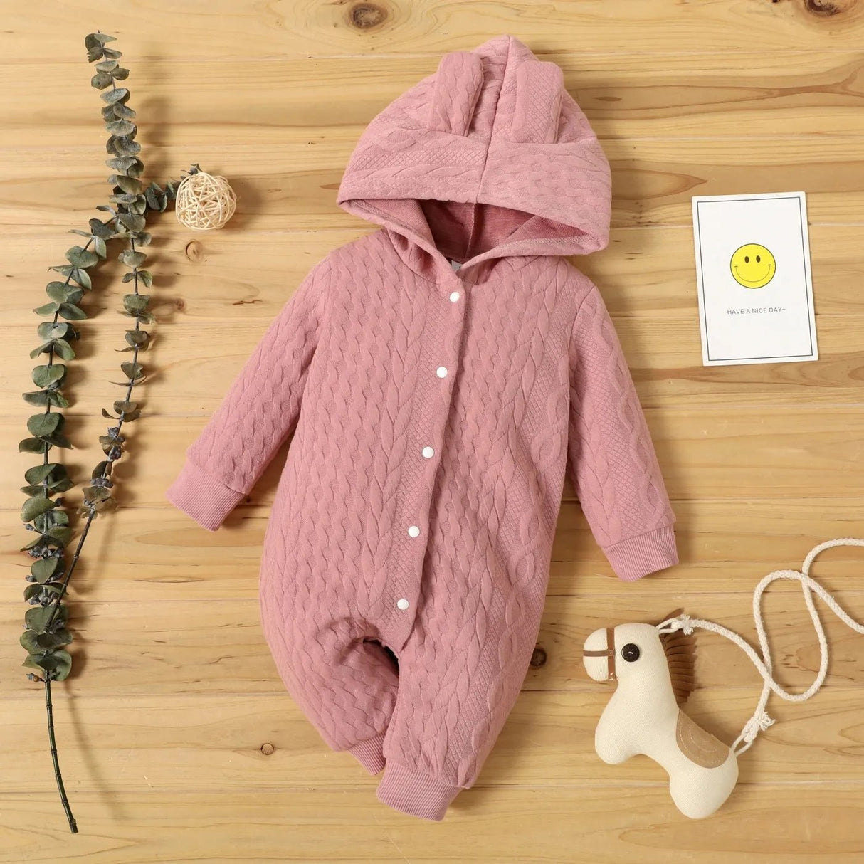 Pink baby snowsuit on a wooden surface