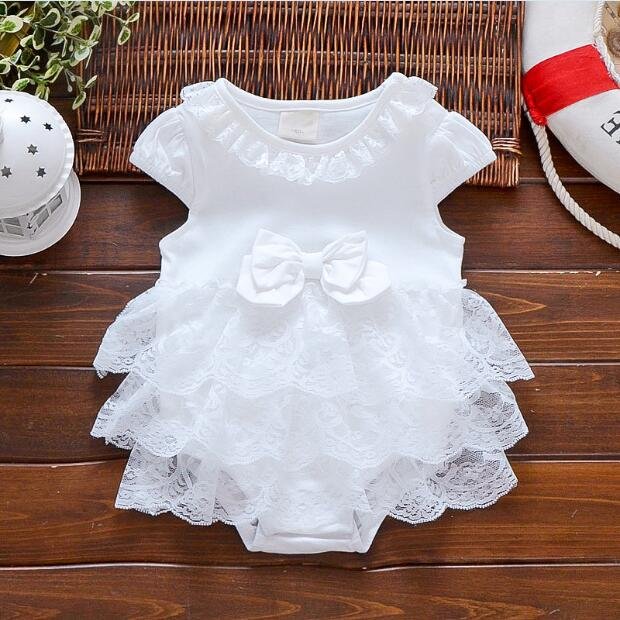 White lace baby dress on a wooden surface
