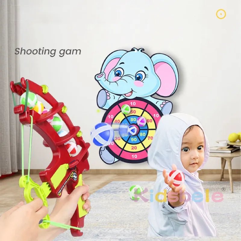 Child playing with a toy archery set aimed at an elephant-themed dartboard.