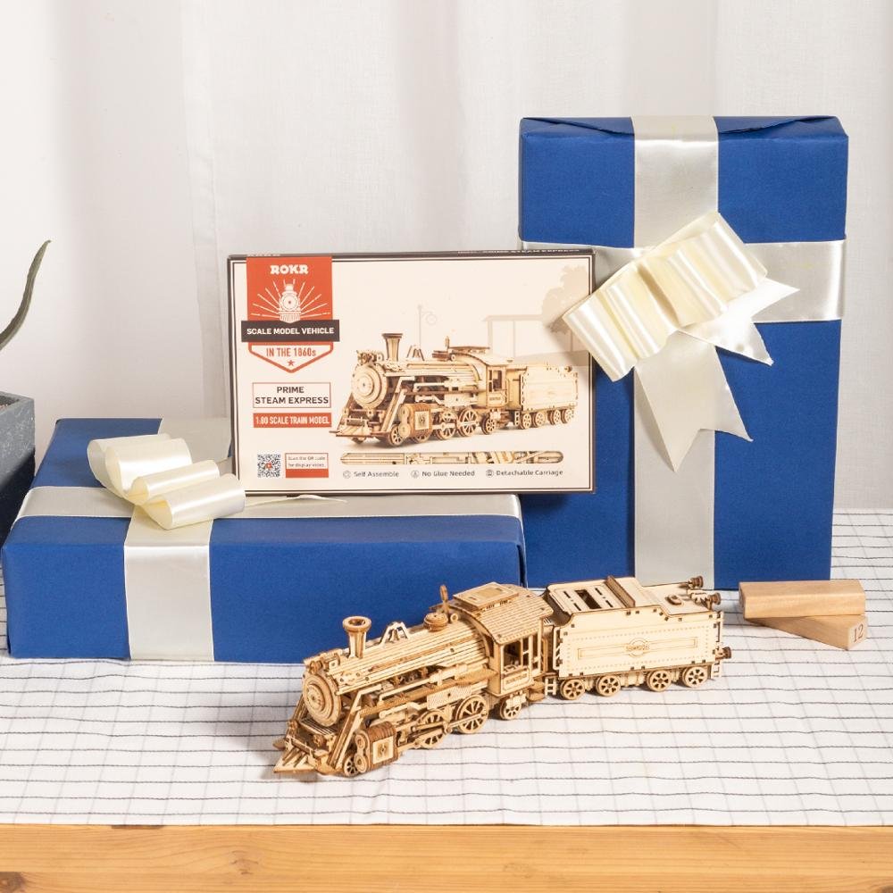 Wooden model train set with packaging and gift box on a checkered tablecloth