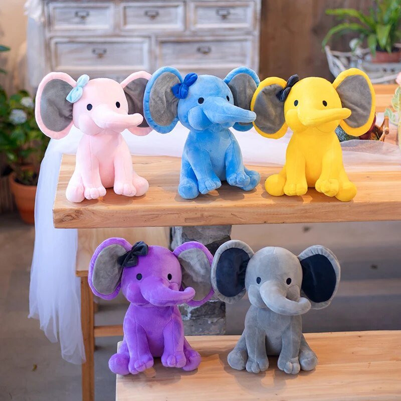 Colorful elephant plush toys on a wooden surface with a blurred indoor background.