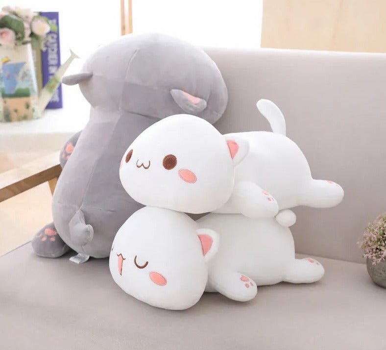Two plush toys, one gray and one white with pink accents, on a light-colored couch.