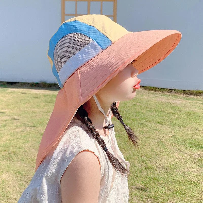 Person wearing a colorful sun hat with a blue and pink design outdoors.