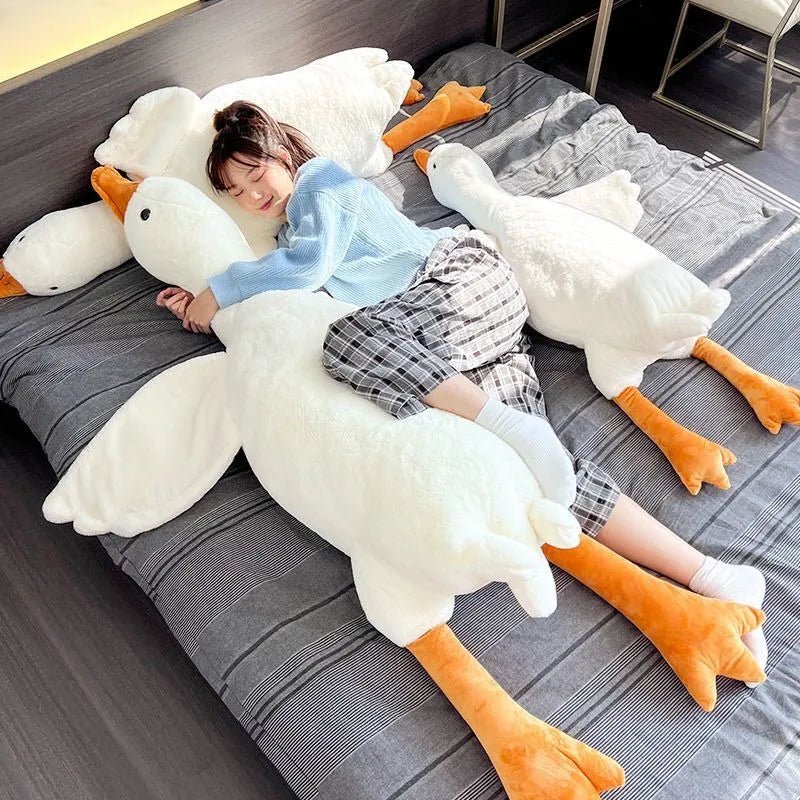 Child lying on a large goose-shaped pillow on a bed