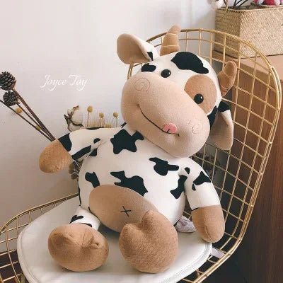 Plush cow toy on a decorative chair with a neutral background
