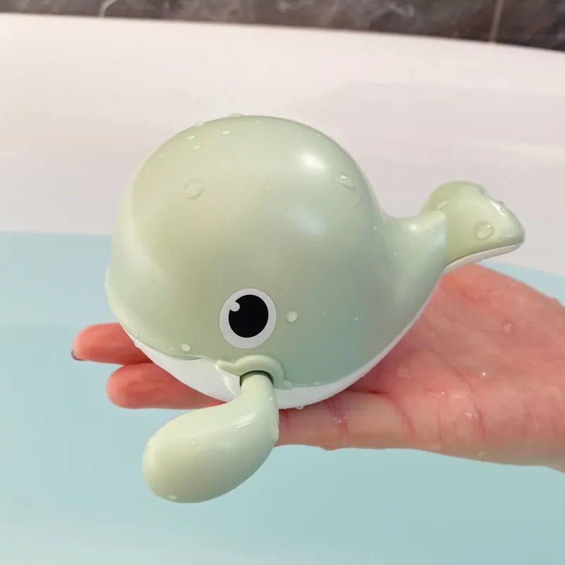 Light green whale-shaped toy held in a hand with a blurred background