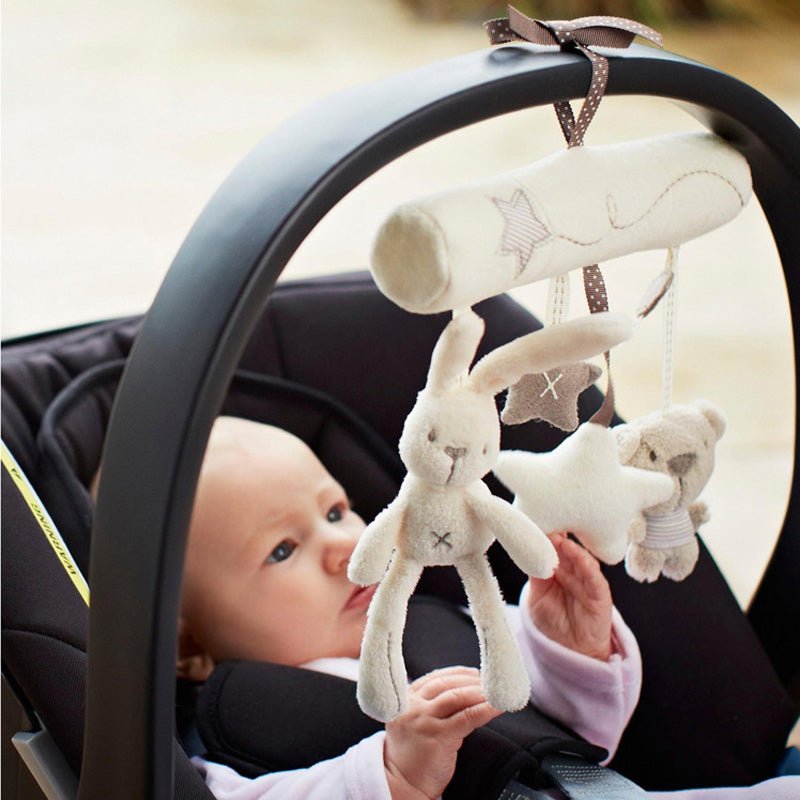 Baby in a car seat with a mobile featuring hanging toys