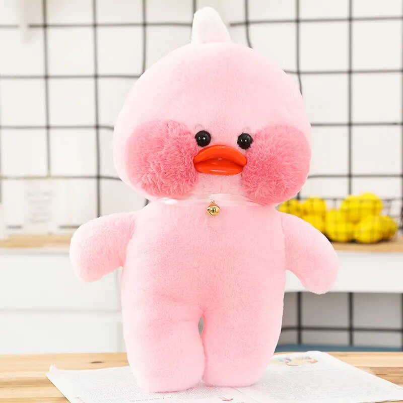 Pink plush toy with a white hat on a wooden surface.
