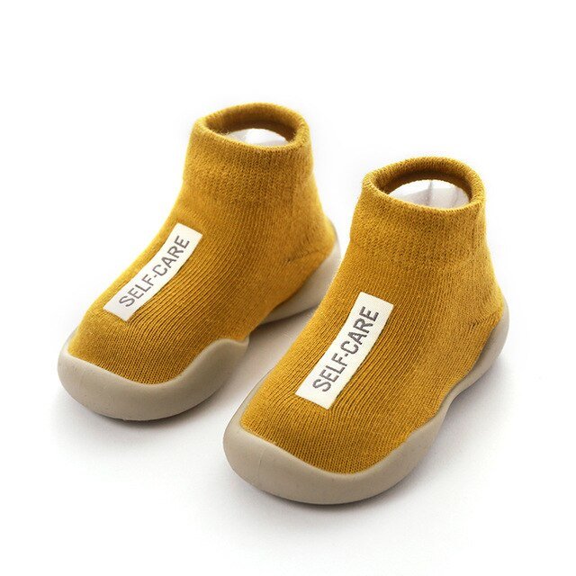 Pair of mustard yellow socks with 'SELF-CARE' label on a white background