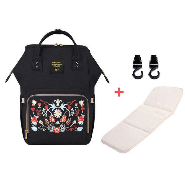 Black backpack with floral embroidery, white mat, and black straps.