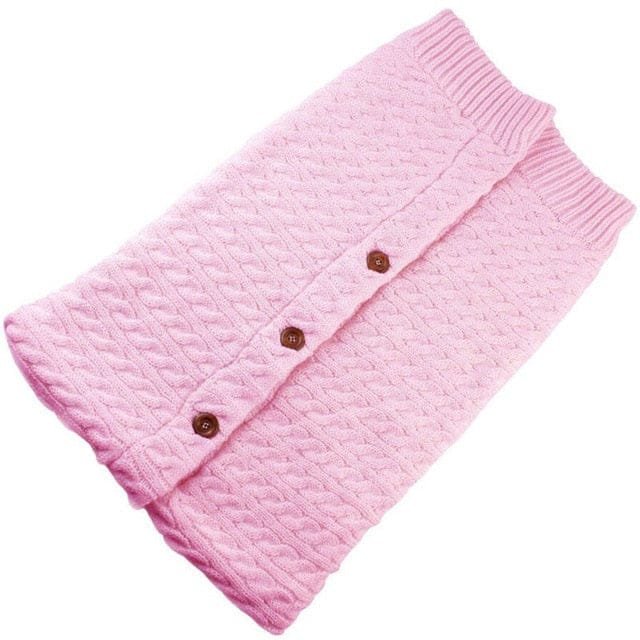 Pink knitted blanket with brown buttons.