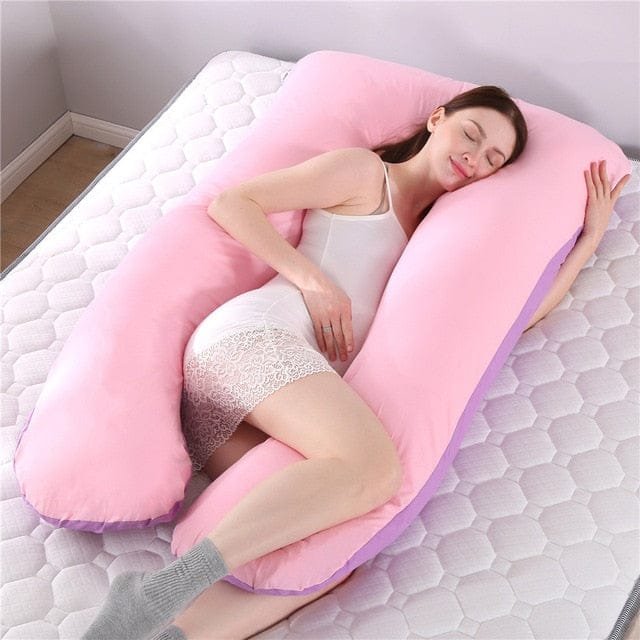 Woman lying on a pink U-shaped body pillow on a bed.