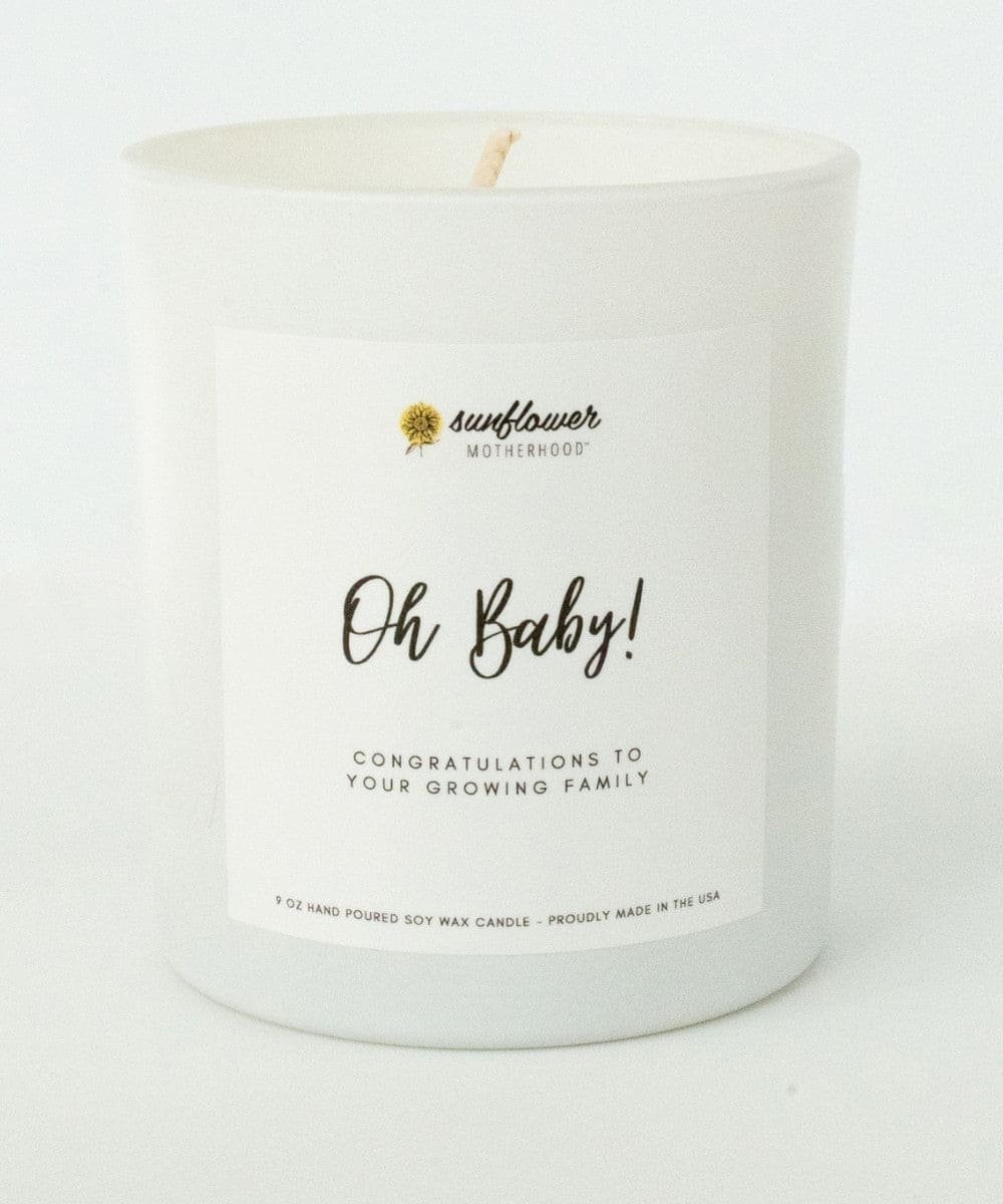 White candle with 'Oh Baby!' text and 'sunflower motherhood' branding.