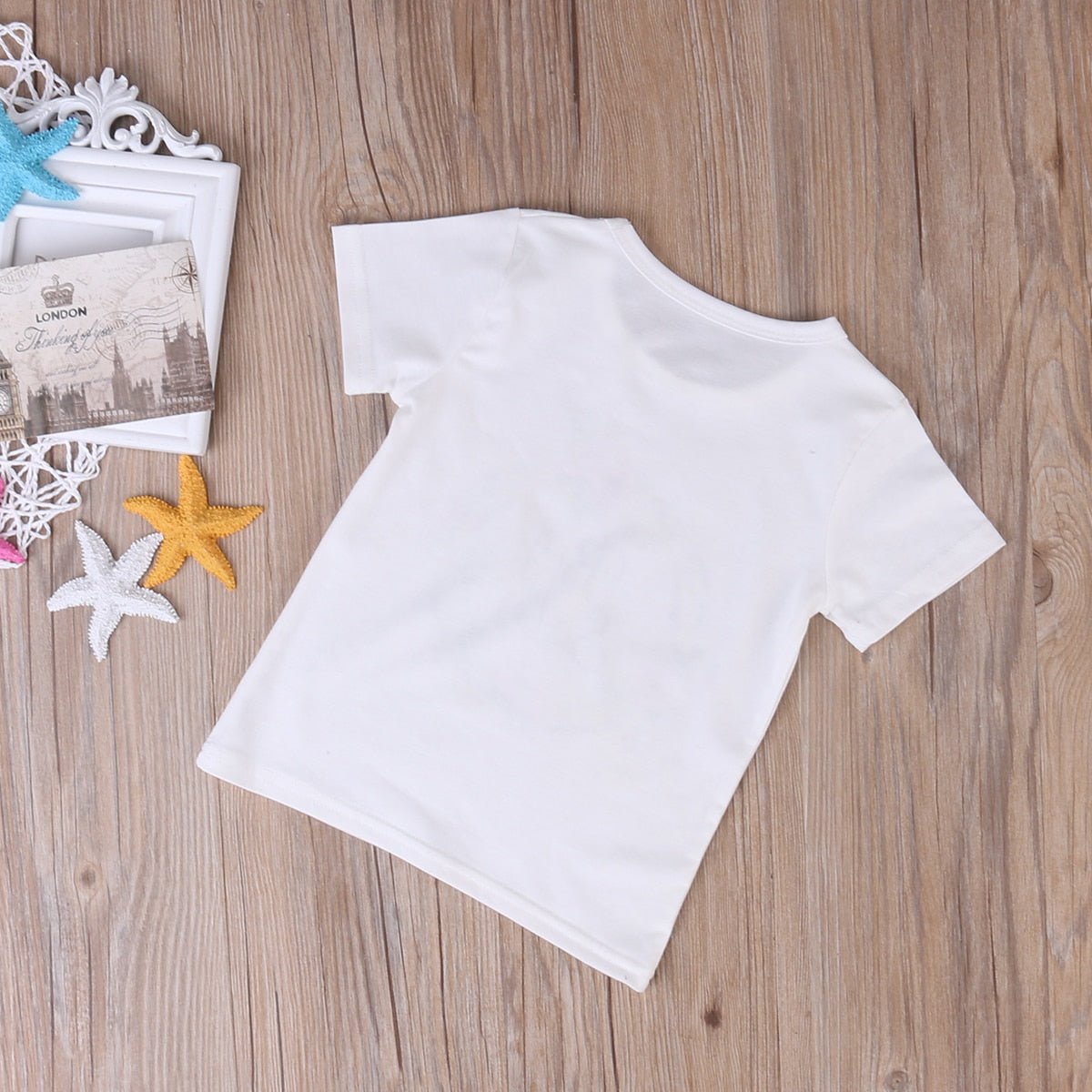 White t-shirt on a wooden surface with decorative items.