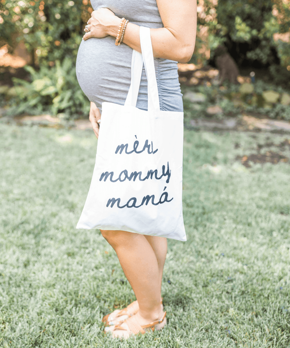Person holding a tote bag with 'més mommy máná' text.