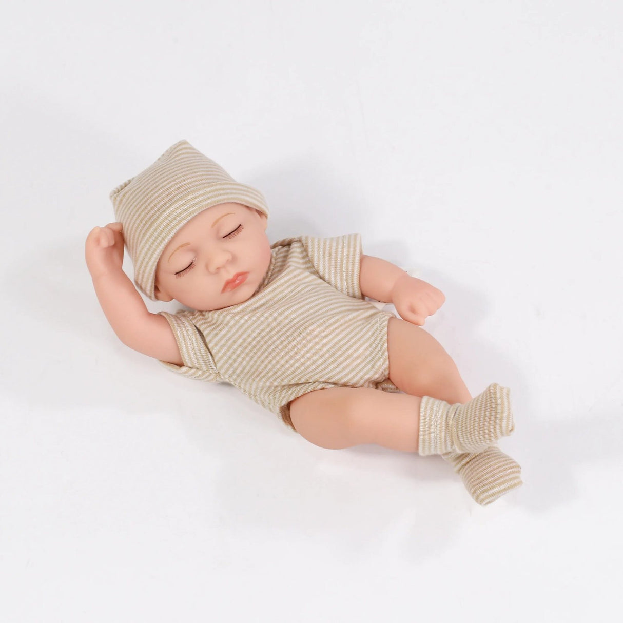 Newborn baby doll wearing a striped outfit and hat on a white background