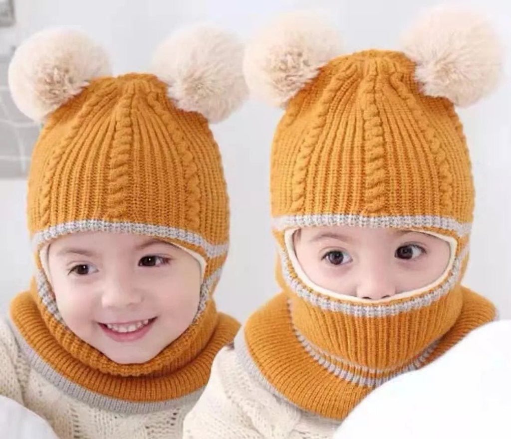 Two children wearing mustard yellow knitted hats with pom-poms and face masks on a light gray background.