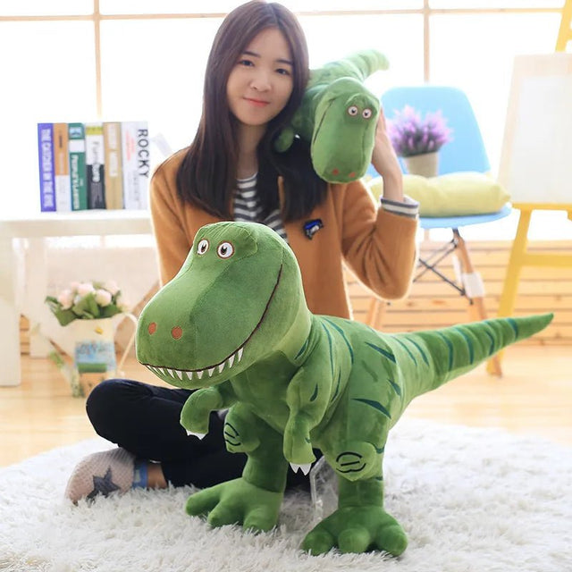 Woman holding a large green dinosaur plush toy in a room with books and a chair.