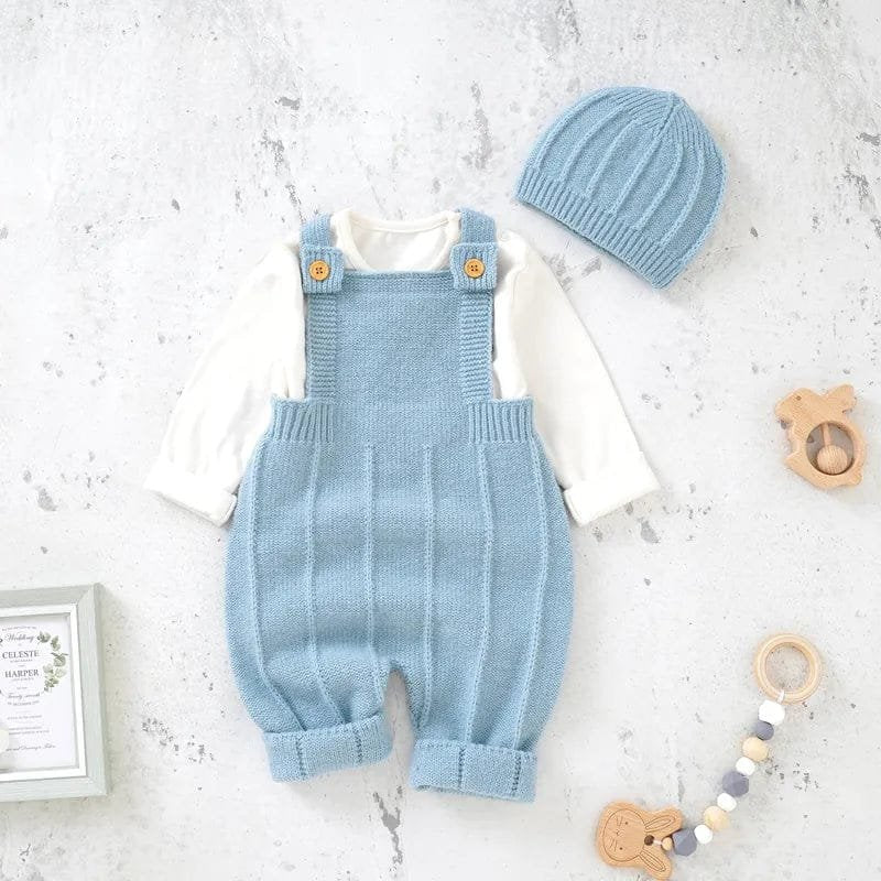 Baby blue knitted romper with matching hat on a light gray surface.