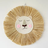 Round woven wall art of a lion face with raffia mane on a white background
