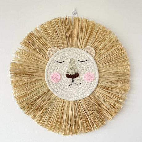Round woven wall art of a lion face with raffia mane on a white background