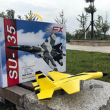 Yellow model airplane in front of its packaging box on a grassy area.