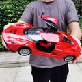 Red 1:14 classical RC car with opening bonnet held outdoors, a model 6066 toy for pretend driving and collecting.