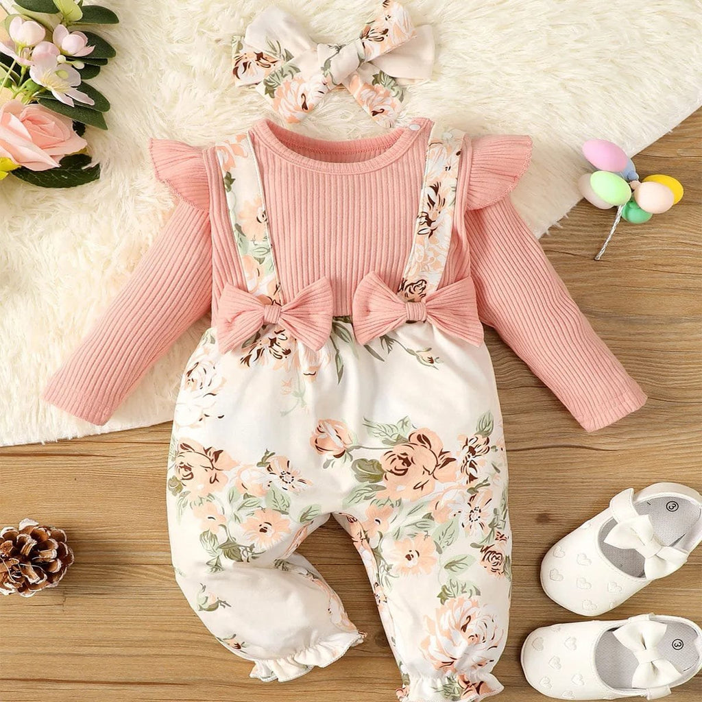 Baby outfit with pink top and floral pants on a wooden surface with flowers and shoes.