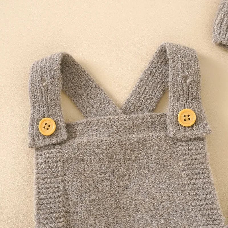 Gray knitted baby romper with yellow buttons on a beige background