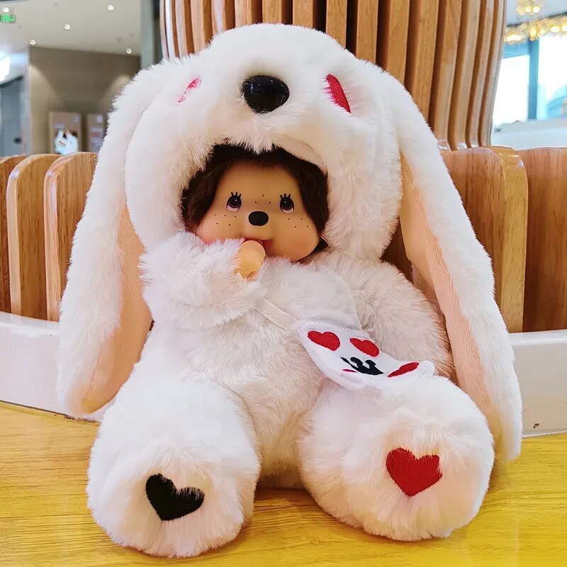 Plush toy with bunny ears and a small doll inside, sitting on a wooden surface.