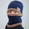 Person wearing a blue knitted hat and scarf with brown trim on a light gray background