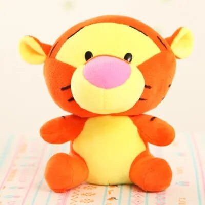 Plush toy tiger with a pink nose on a colorful blanket.