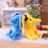 Blue elephant and yellow dog plush toys on a table with a blurred background