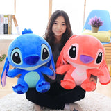 Person holding two plush toys, one blue and one pink, in a room setting.