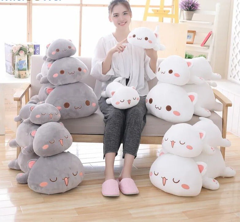 Woman sitting on a chair surrounded by various plush toys in a bright room.